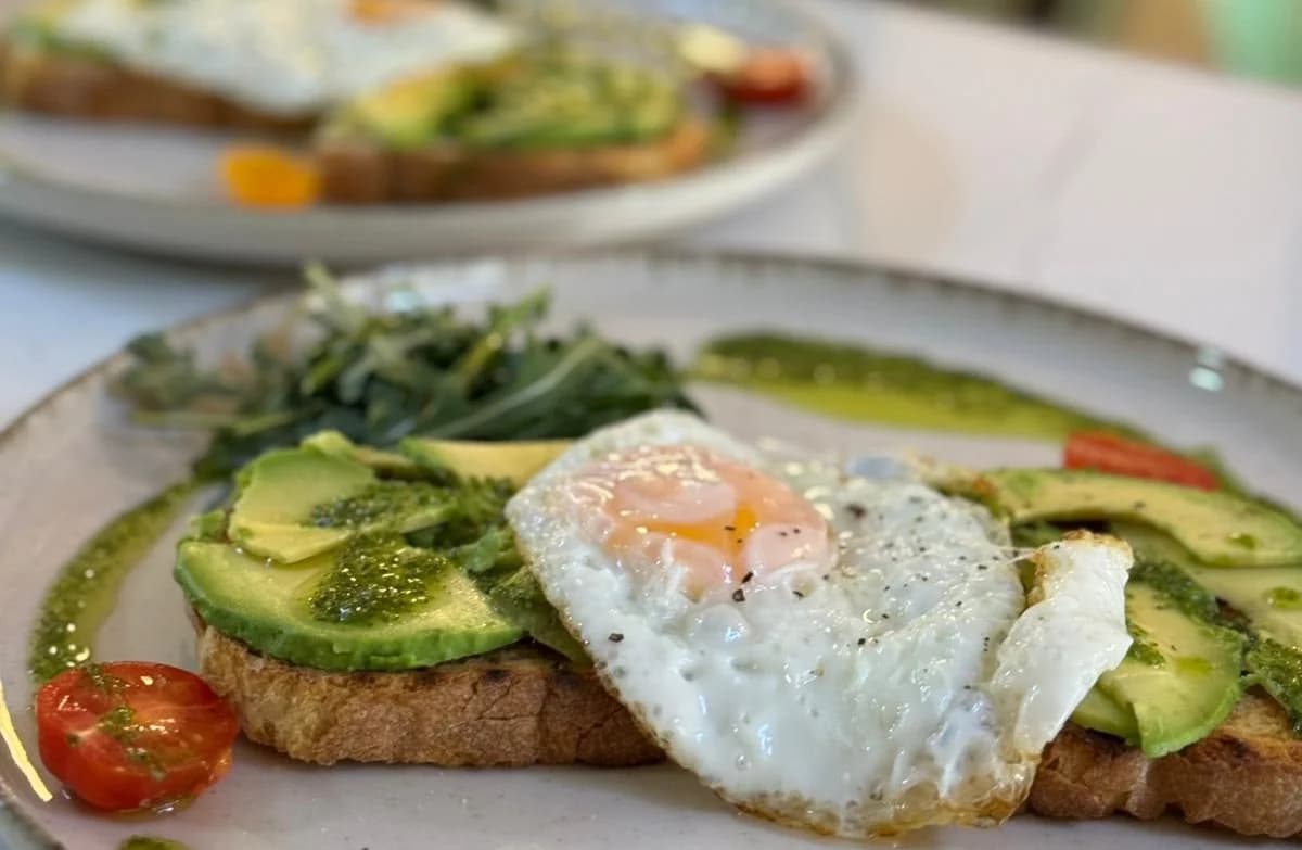 Tostada de aguacate con huevo frito, rúcula y tomates cherry en Nomada Restaurant & Brunch en Figueres, Girona